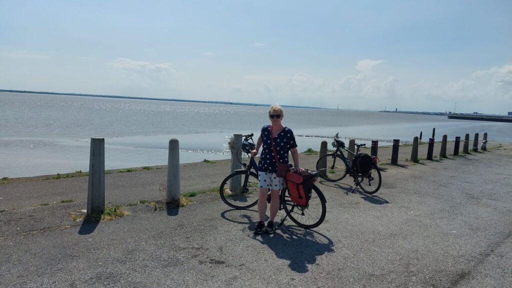 author with bicycle on quayside looking from North bank of Humber Estuary towards Hull showing South bank